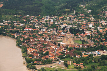 Mtskheta, Georgia, displaying Svetitskhoveli cathedral and historic buildings along the Kura river, offering a panoramic aerial view of the ancient capital and its green surroundings © yaroslav1986