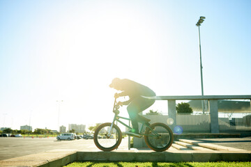 Naklejka premium BMX, man and bicycle in city for exercise, eco friendly travel and cycling with space. Person, riding bike and cyclist on curb outdoor for fitness, urban sports and balance for cardio with flare