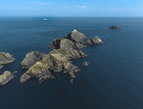 Aerial view of Muckle Flugga Lighthouse perched on rugged rocky cliffs surrounded by the deep blue North Sea in the Shetland Islands, Scotland, United Kingdom.