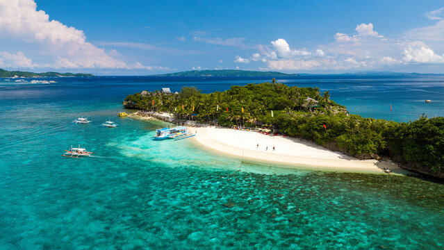 Aerial view of Boracay Island featuring white sand beach, turquoise waters, outrigger boats, and lush tropical vegetation in Malay, Western Visayas, Philippines.