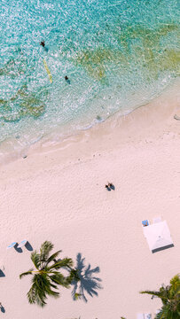 Aerial view of Boracay Island with white sand beach, turquoise water, palm trees, and people swimming in Malay, Western Visayas, Philippines.
