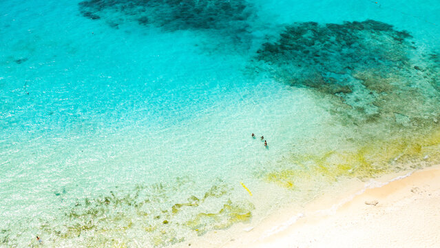 Aerial view of Boracay Island featuring crystal clear turquoise water, coral reefs, and people swimming near the white sandy beach in Malay, Western Visayas, Philippines.