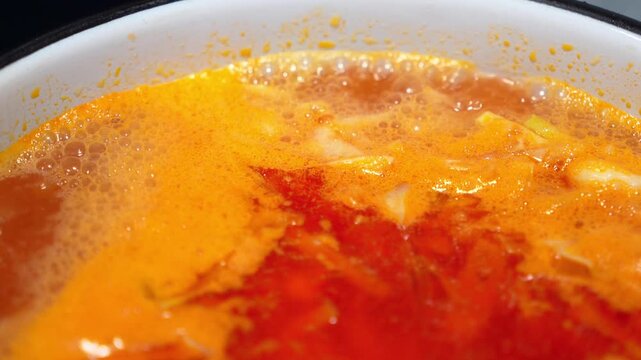 Hot traditional Russian shchi cabbage soup boiling in a pot on a stove indoors. Red vegetable broth meal in the process of cooking, homemade culinary recipe dinner preparation layout space area.