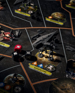 Imperial star destroyer AT-AT walker and stormtrooper miniatures with combat dice on Mandalore planet board game map representing imperial conquest