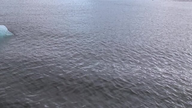 Calm gray water and gentle surface ripples fill a minimal cold seascape. The image retains natural light and surface texture as secondary detail, while light and texture shape the wider scene.