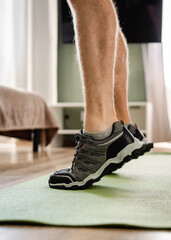 Fototapeta premium Person lifting heels to exercise calves on mat in morning home setting