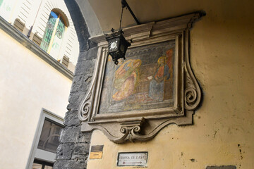 Seventeenth century street shrine tabernacle of Santissima Annunziata copy with a directional sign to the Church of Dante Alighieri, Florence, Tuscany, Italy © Simona Sirio