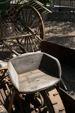 Rustic Weathered Wooden Seat of an Abandoned Vintage Farm Implement in Harsh Sunlight