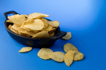 Aperitivo de patatas fritas crujientes en plato negro mate sobre fondo azul © Alex Manzanares