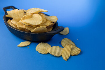 Aperitivo de patatas fritas crujientes en plato negro mate sobre fondo azul © Alex Manzanares