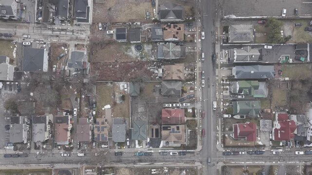 Drone tilts up from neighborhood streets to a hazy city horizon. The camera reveals a wider cityscape from a close view of streets and low rise roofs.