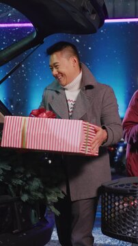 Young beautiful couple pf multi-cultural parents packing holiday presents for whole family having fun communicatin on parking space. Parked car. Winter time. Christmas coming.
