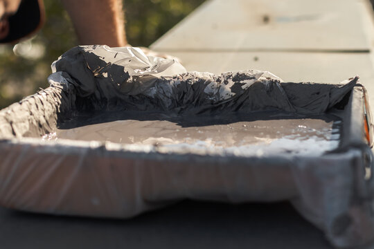 A paint tray sitting on a cornice on a sunny day.