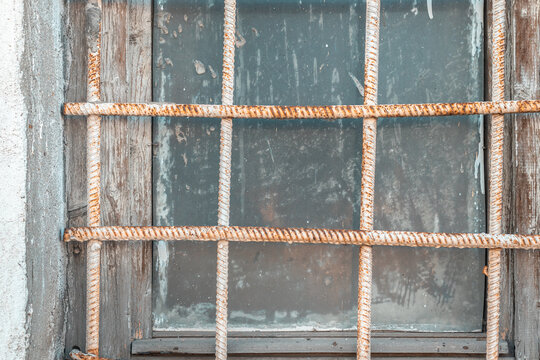 An old dirty window with an old rusty grate