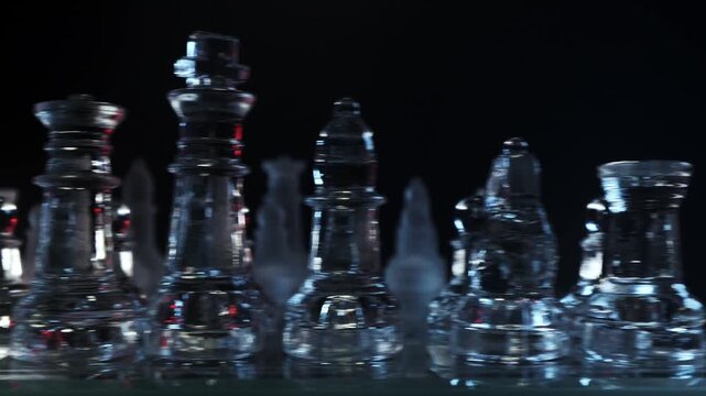 Low-angle close-up camera motion panning horizontally past glowing glass chess pieces on a dark background.