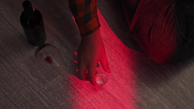 Man's hand reaches for a glass of alcohol.