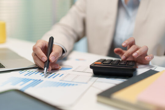 Business Analyst Reviewing Financial Charts with Calculator