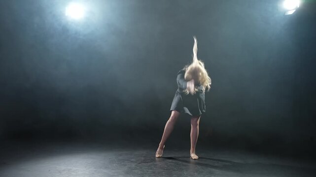 Contemporary woman dancer posing on black background with smoke. Adult female artist performer dancing with expression. Modern ballerina dancing in darkness. Passion dance in dark. Flexibility balance