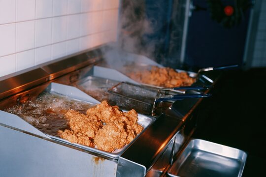 Deep fryers bubbling with breaded turkey cutlets in a professional kitchen, steaming and golden for festive holiday restaurant features