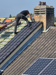 Ouvrier qui rénove la toiture d’une maison pour isolation et remplacement des tuiles © joef