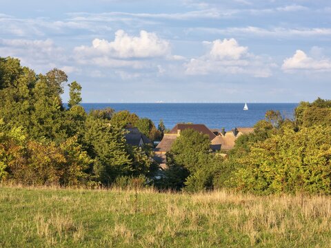 View over the thatched roofs of the fishing village of Vitt to the Baltic Sea, a sailboat on the water, Cape Arkona, R&uuml;gen island, Mecklenburg-Western Pomerania, Germany