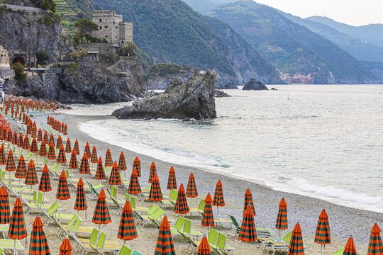 Sun loungers and parasols, boulders on the beach di Fegina, behind the Torre Aurora Mare, Monterosso al Mare, Cinque Terre, Ligurian Coast, Liguria, Italy
