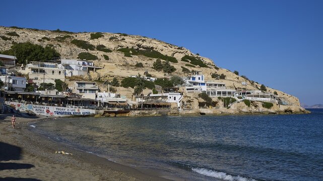 Houses in a village on the seashore with sunny beach and blue sky, Matala, South Coast, Crete, Greek Islands, Greece