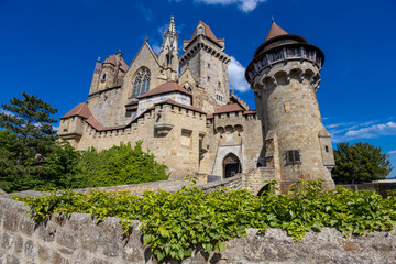 Historic castle in Austria surrounded by picturesque countryside and lush alpine scenery, presenting a timeless European architectural landmark beneath a dramatic sky. The elegant fortress © Yuliia