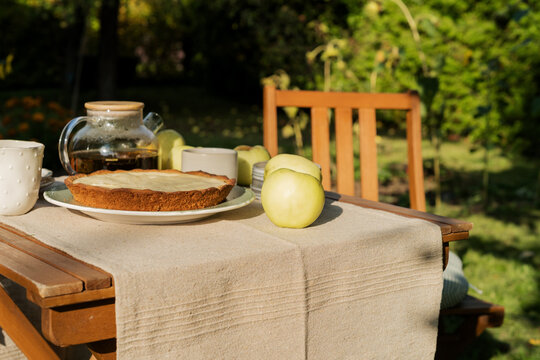 Homemade apple pie and hot tea on cozy wooden garden table