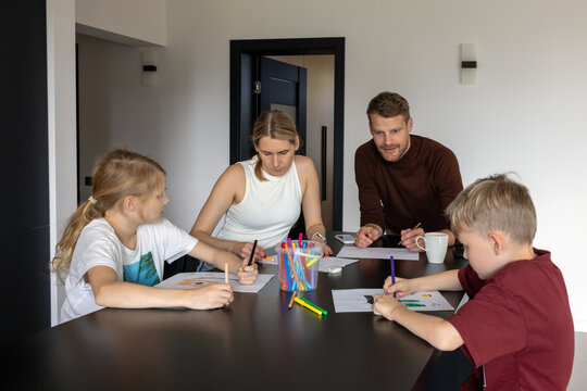 Happy family with two children playing drawing game together at home. Quality time