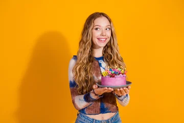 Fotobehang Bosdieren Young girl with blonde hair presents pink birthday cake with candles against a bright yellow background  © deagreez