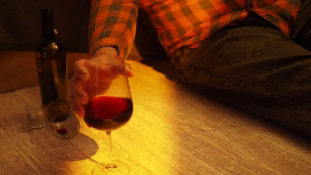 Man's hand reaches for a glass of alcohol.
