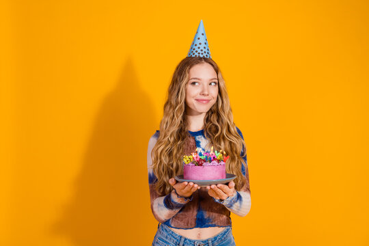 Young blonde girl birthday celebration with a pink cake and party hat against a bright yellow background perfect for promotion and lifestyle imagery
