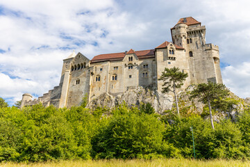 Historic castle in Austria surrounded by picturesque countryside and lush alpine scenery, presenting a timeless European architectural landmark beneath a dramatic sky. The elegant fortress © Yuliia