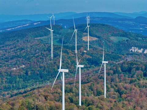 Aerial view of Parc eolien du Lomont with wind turbines rising above a dense autumn forest in Vyt-les-Belvoir, Bourgogne-Franche-Comte, France.