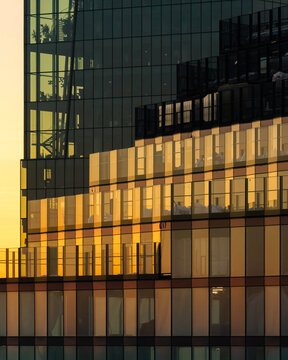 Aerial view of modern glass skyscraper facade reflecting golden sunset light in Warsaw, Masovian Voivodeship, Poland.