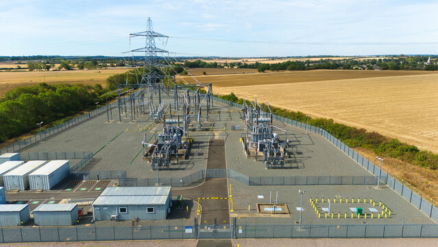 Aerial view of the National Grid Ryhall Substation 400 kV, Energy Park, featuring electrical transformers and high-voltage power lines surrounded by fields in Ryhall, England, United Kingdom.