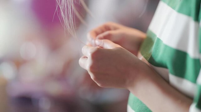 Person examining a strand of hair with their hands