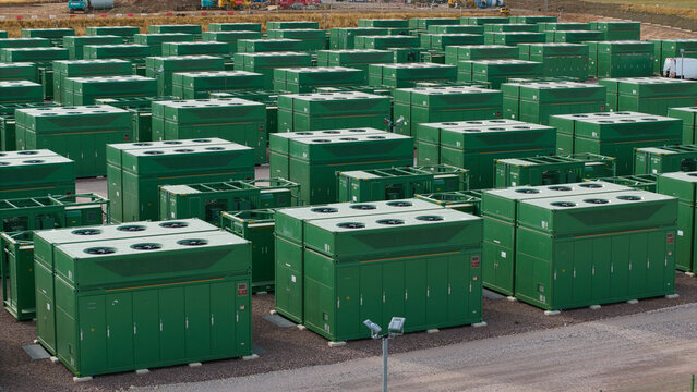 Aerial view of a large battery energy storage system with rows of green containerized battery units and cooling fans in Coleshill, England, United Kingdom.