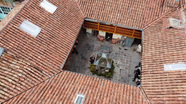 Aerial view of a traditional colonial courtyard with terracotta tile roofs, stone paving, and a wooden balcony in the historic center of Cusco, Cusco, Peru.