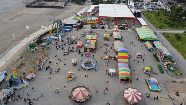 Aerial view of the Costa Verde fairground featuring colorful amusement rides, tents, and visitors walking through the park in San Miguel, Lima Province, Peru.