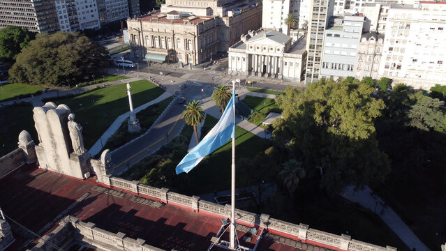 Aerial view of the Argentine flag waving on a rooftop with the historic Teatro Colon and Plaza Lavalle in the background in Buenos Aires, Buenos Aires, Argentina.