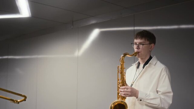 Caucasian young adult musicians playing trombone and saxophone in modern urban pedestrian tunnel. Footage fits jazz festival promotions, arts education campaigns, urban youth culture commercials