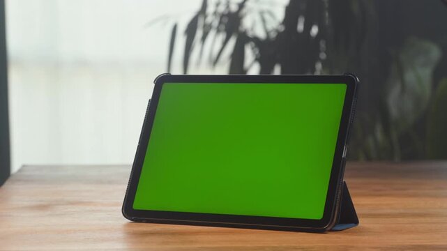 Tablet with green screen, close up of tablet pc chroma key mockup on table, hand touching blank green display, app template and copy space for presentation
