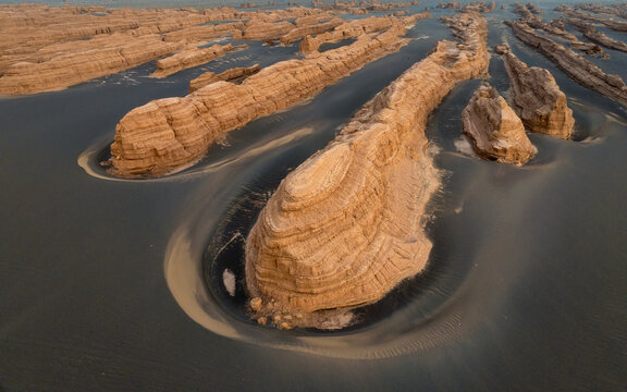 Aerial view of Yadan National Geological Park, featuring wind-eroded rock formations rising from dark desert sands in Jiuquan, Gansu, China.