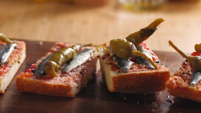 Pan con tomate with anchovies and guindilla pepper, close up of classic Spanish tapas gilda with marinated boquerones on tomato bread, Spanish cuisine bar snack