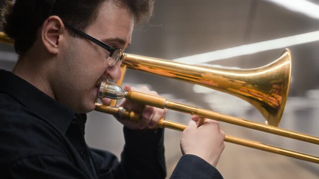 Young adult Caucasian musician playing trombone in modern urban underpass. Footage suitable for music school advertising, jazz concert promotions, cultural arts documentaries