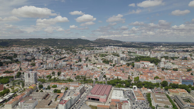 Aerial view of the city of Setubal with its dense urban landscape, terracotta rooftops, and historic buildings under a blue sky in Setubal, Setubal, Portugal.