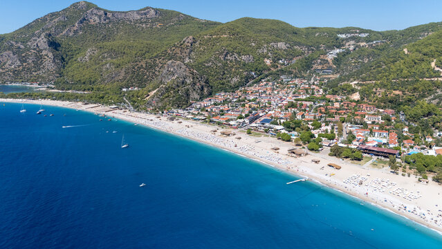 Aerial view of Oludeniz beach with turquoise waters, sandy coastline, and surrounding green mountains in Oludeniz, Mugla, Turkiye.