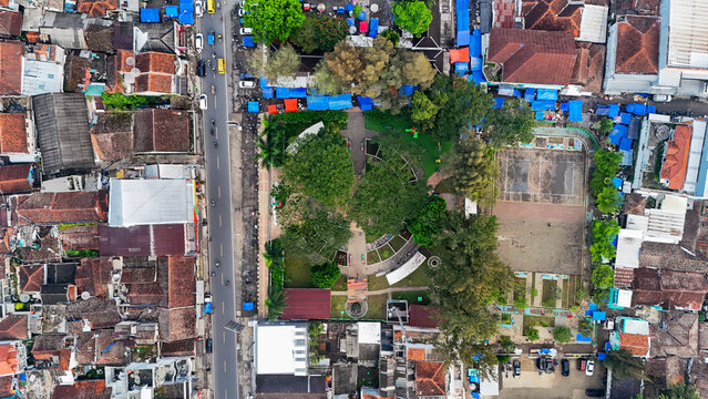 Aerial view of the Ciwidey town square featuring a basketball court, lush green trees, and surrounding urban rooftops in Bandung, West Java, Indonesia.